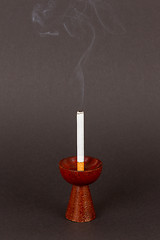 Image showing Burning cigarette in a candleholder