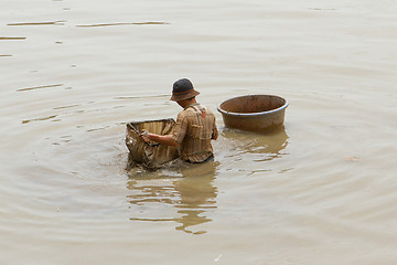 Image showing A vietnamese fisherman is searching for shells in the water