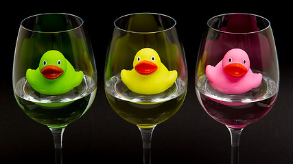 Image showing Green, yellow and pink rubber ducks in wineglasses