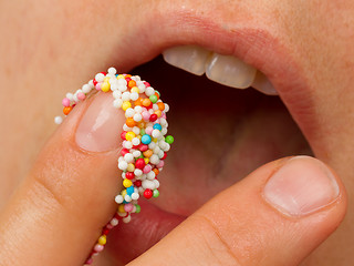 Image showing Woman lips and finger with multicolored pearls 