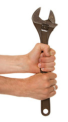 Image showing Old rusted adjustable vector wrench in a hand