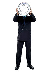 Image showing Executive holding up wall clock in front of his face