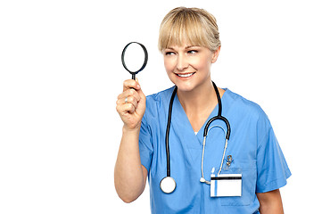 Image showing Pretty physician looking through magnifying glass