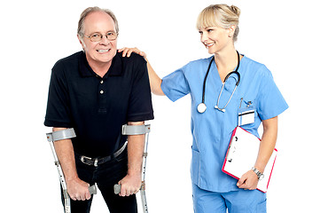 Image showing Cheerful doctor encouraging her patient to walk with crutches