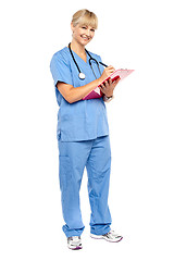 Image showing Smiling nurse preparing case sheet of a patient