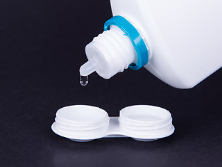 Image showing Lens casing and bottle of water isolated on black