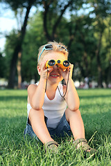 Image showing Little boy sitting in the park with a binoculars