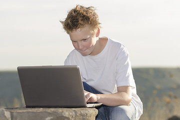 Image showing Schoolboy play the game on laptop