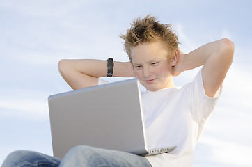 Image showing Fair-haired schoolboy relaxing hands behind his head