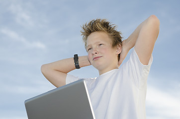 Image showing Resting teenager with laptop holding hands behind his head again