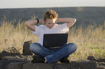 Image showing  Teen rest with laptop hold hands behind his head