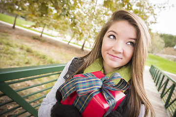 Image showing Pretty Woman with Wrapped Gift with Bow Outside