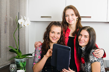 Image showing Three young women friends chatting at home and using laptop to l