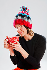 Image showing Smiling woman in knitted hat holding cup