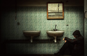 Image showing An abandoned industrial interior with a depressed man