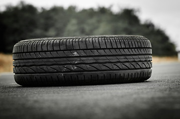 Image showing Abandoned car tyre on the road with green background