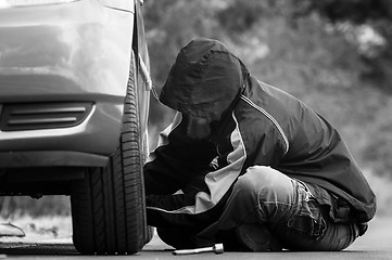 Image showing Young adult inspecting the wheel