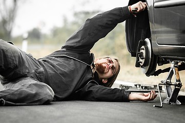 Image showing Handsome young man repairing car