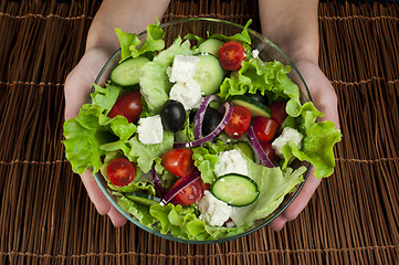 Image showing Hands holding salad in a glass bowl 