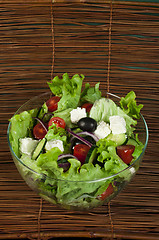 Image showing Salad in a glass bowl on a wooden base