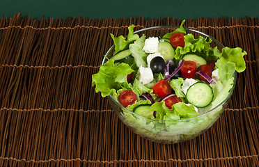 Image showing Salad in a glass bowl on a wooden base
