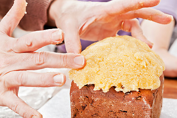 Image showing Hands decorating christmas cake closeup