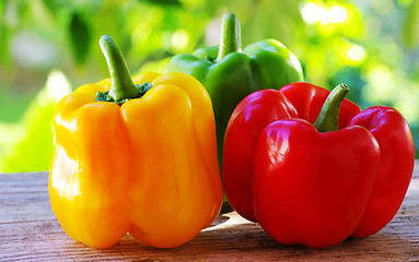 Image showing red, yellow and green pepper on table,green background 