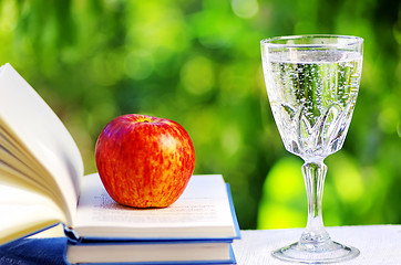 Image showing Apple on open book and water cup