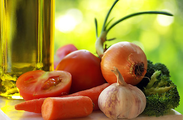 Image showing Olive oil and vegetables in green background.