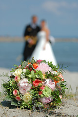 Image showing Bouquet, bride and groom. Focus on the bouquet.