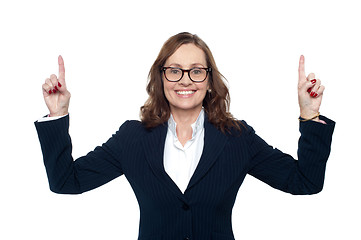 Image showing Smiling corporate woman pointing upwards
