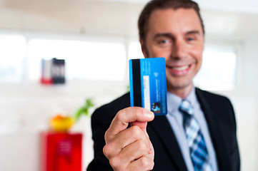 Image showing Cheerful businessman holding up his credit card