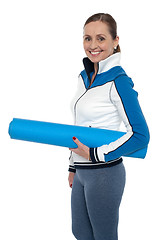 Image showing Woman carrying blue yoga mat