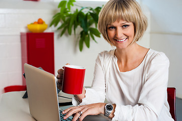 Image showing Cheerful woman holding coffee mug and working