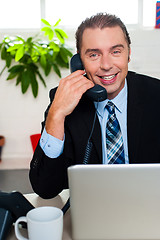 Image showing Smiling male manager attending clients call