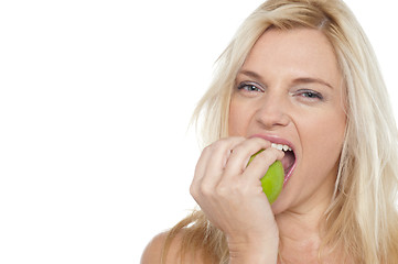 Image showing Sexy blonde female eating fresh green apple