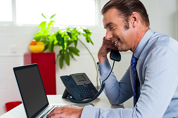 Image showing Side profile of a businessman busy in office work