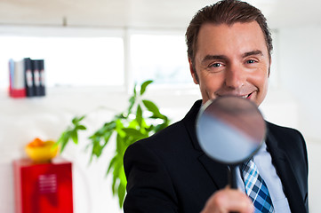 Image showing Business executive holding magnifying glass