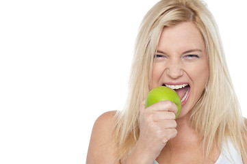 Image showing Closeup shot of a blonde woman biting an apple