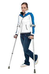 Image showing Pensive looking woman using crutches to walk