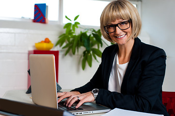 Image showing Smiling female manager typing report on laptop