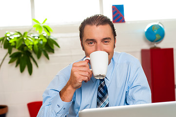 Image showing Smiling male manager enjoying hot coffee