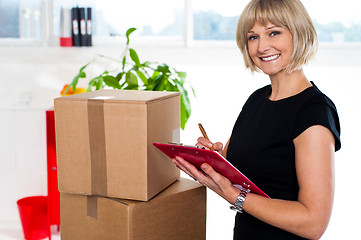 Image showing Casual woman documenting list of goods on clipboard