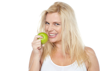 Image showing Health conscious woman about to take bite from green apple
