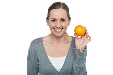Image showing Portrait of a woman holding up an orange