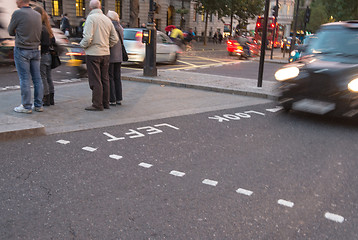 Image showing Motion blur picture of Black Taxi approaching Look Right sign in