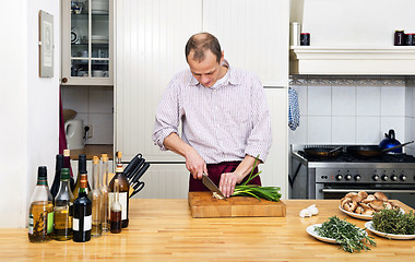Image showing Man Cutting Spring Onions In Kitchen