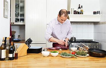 Image showing Man Cutting Meat On Chopping Board