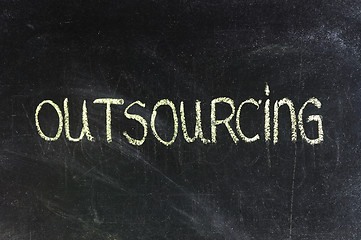 Image showing outsourcing word in white chalk handwriting on blackboard 