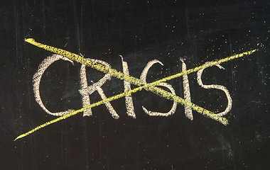 Image showing Crossing out crisis on a green chalkboard